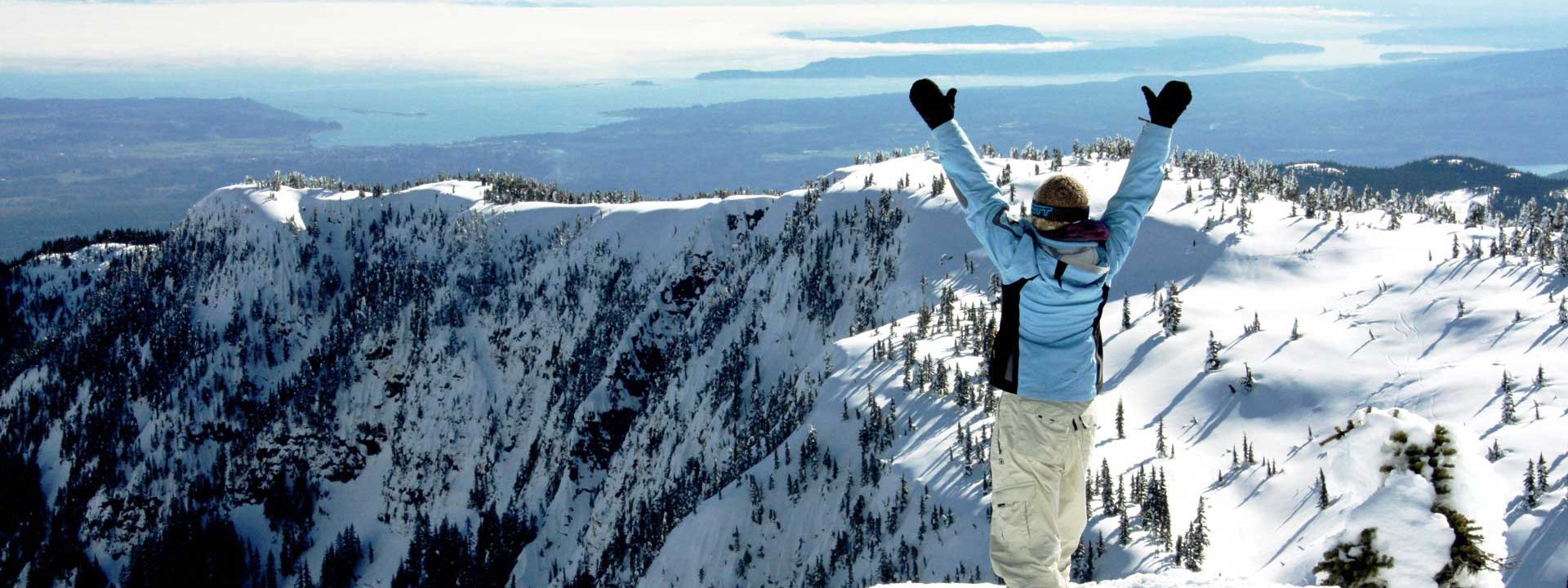 person standing on top of a snowy mountain with their hands up in the air