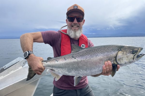 Man holding a large fish on a boat in the ocean off the coast of Vancouver Island